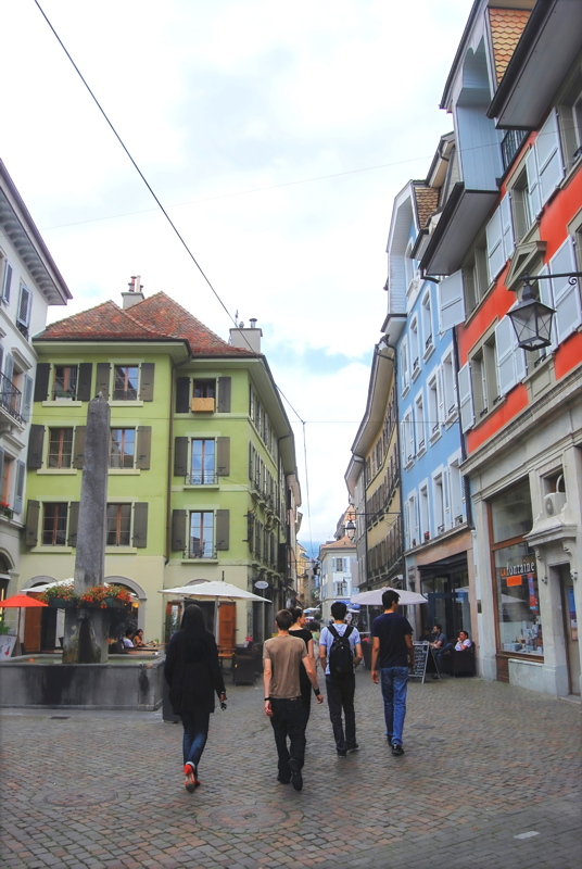 22 - A scenic cobblestone street in the old town of Vevey, Switzerland, featuring historic colorful buildings and an old stone fountain